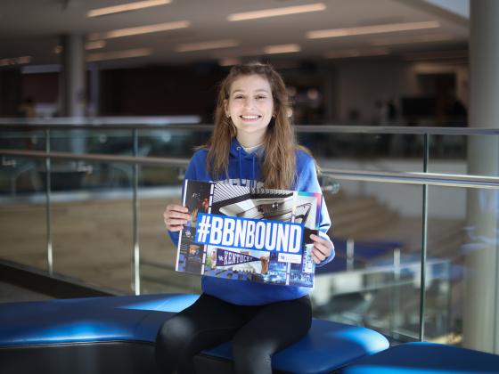 student in student center with welcome packet brochure