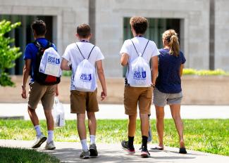 Students walk across campus at orientation with seeblueU backpacks.