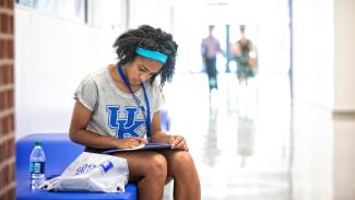 An incoming student sits on a bench looking through an orientation folder at seeblue U.