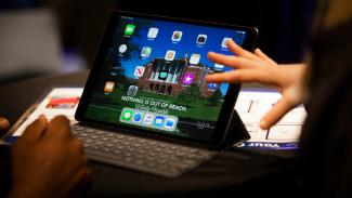 A close up of a person using an iPad for connecting to see blue. U virtually.