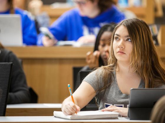 A female student sits in a classroom taking notes.