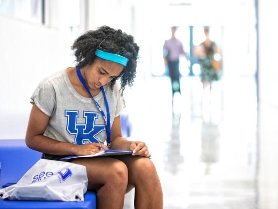 An incoming student sits on a bench looking through an orientation folder at seeblue U.